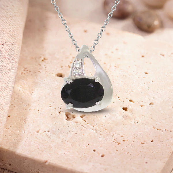 Pendentif onyx facetté, modèle ovale facetté sur griffes, sur sa chaîne, posé sur une dalle de travertin