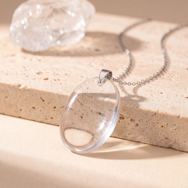 Pendentif pierre transparente ovale en cristal de roche, plat et poli, sur chaîne argentée et travertin