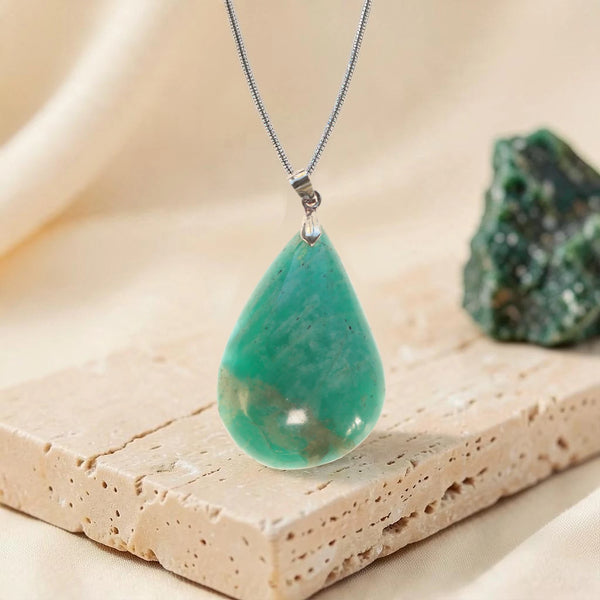 Pendentif pierre verte en amazonite pièce unique, goutte turquoise sur chaîne argentée posée sur travertin