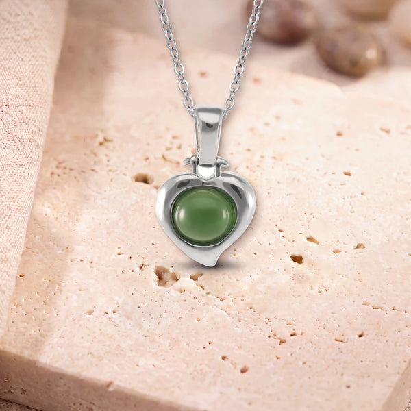 Pendentif jade véritable, modèle en cœur d'argent, sur sa chaîne, posé sur une dalle de travertin