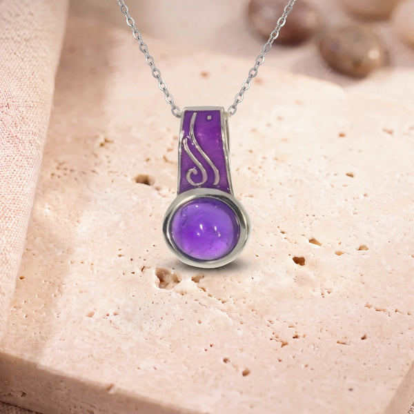 Pendentif améthyste naturelle, modèle rond à bélière émaillée, sur sa chaîne, posé sur une dalle de travertin