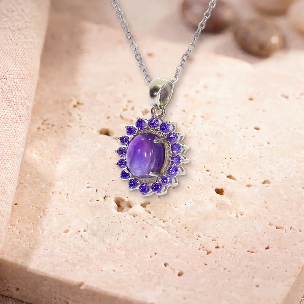 Pendentif améthyste femme, modèle médaillon ovale bordé de zircons, sur sa chaîne, posé sur une dalle de travertin