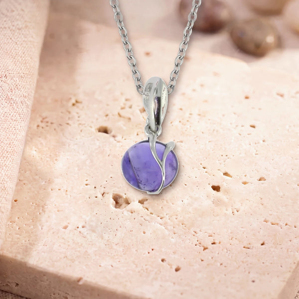 Collier améthyste argent, modèle rond enlacé d'une liane d'argent, sur sa chaîne, posé sur une dalle de travertin