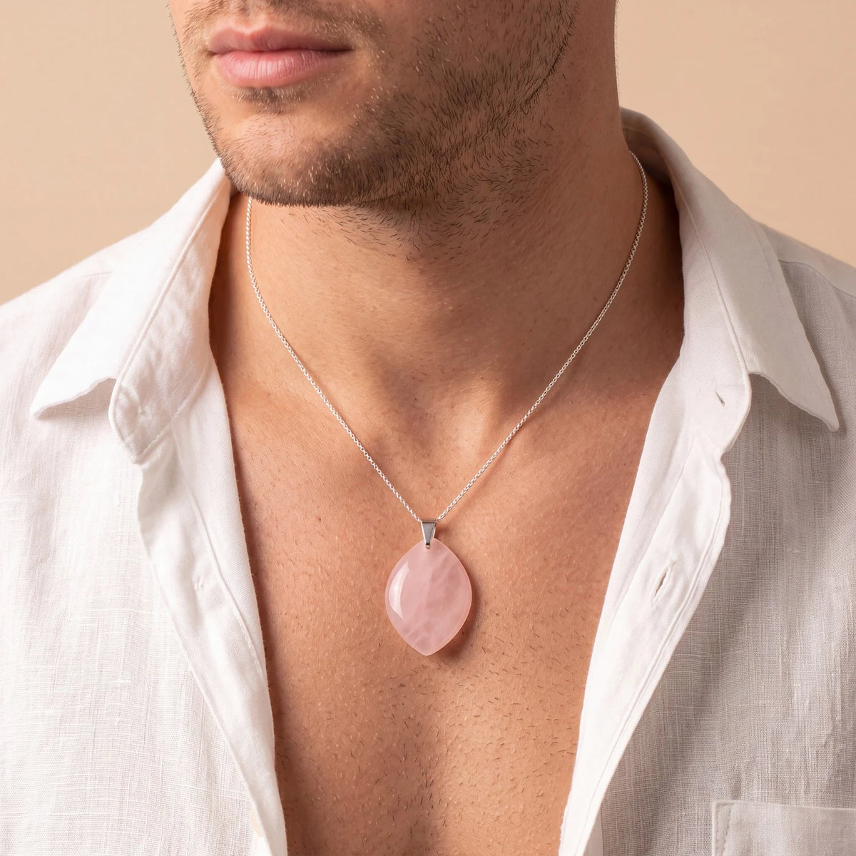 Pendentif quartz rose forme libre porté par un homme sur une chemise ouverte