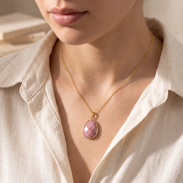 Pendentif rhodonite porté par une femme, collier pierre rose sur chaîne dorée