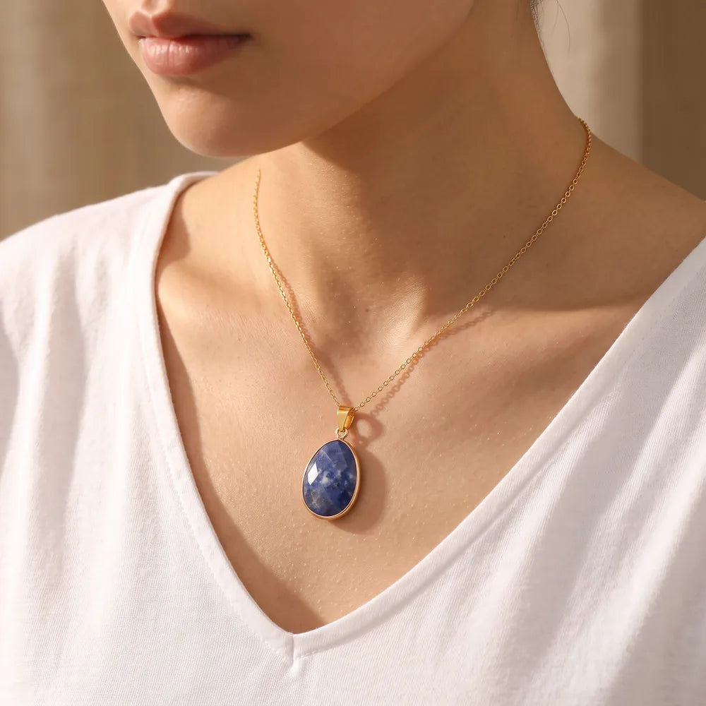 Pendentif sodalite porté par une femme, pendentif pierre bleue sur chaîne dorée