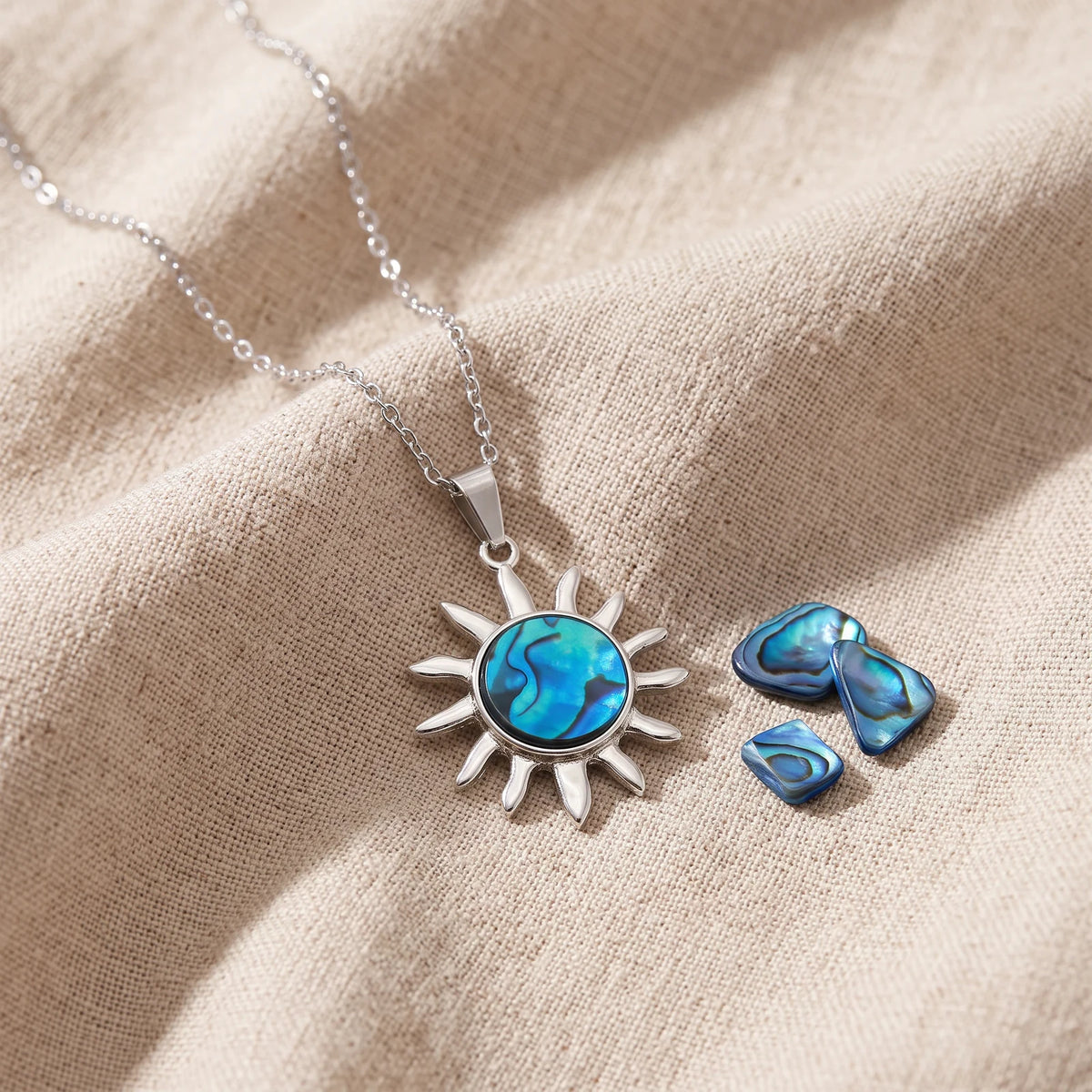 Pendentif soleil en nacre d'ormeau bleue sur un lin naturel avec des éclats de nacre