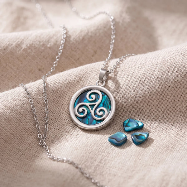 Pendentif triskel en nacre d'ormeau bleue sur un lin naturel avec des éclats de nacre