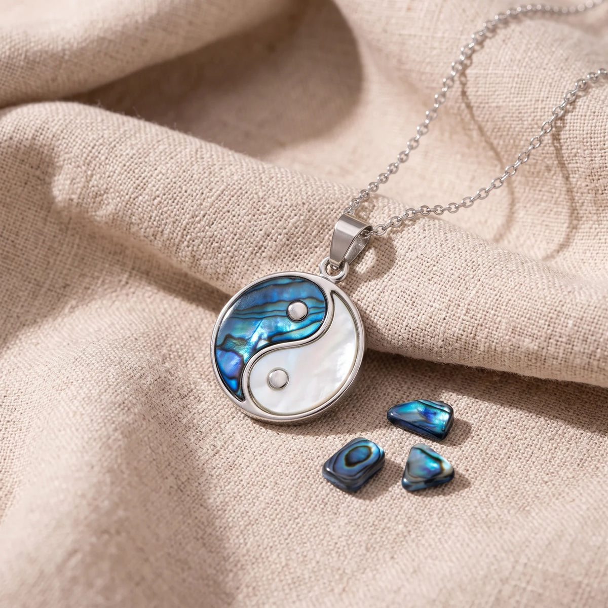 Pendentif yin yang en nacre d'ormeau bleue sur un lin naturel avec des éclats de nacre