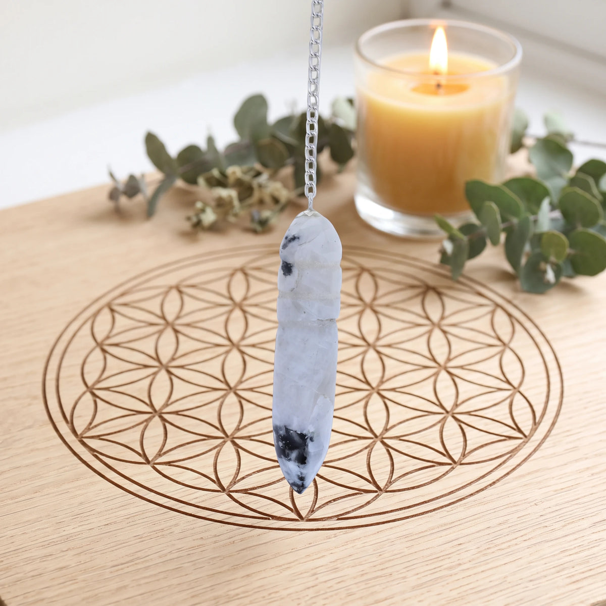 Pendule blanc égyptien en pierre de lune pour la radiesthésie sur planche Fleur de Vie