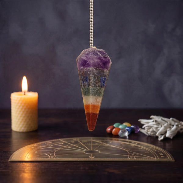 Pendule de magnétiseur chakra facetté en pierres naturelles multicolores, près d'une bougie