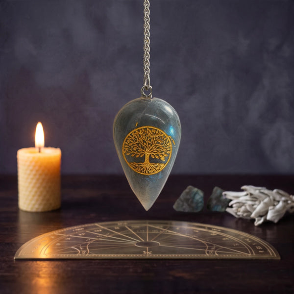 Pendule en labradorite gravé Arbre de Vie pour la divination, suspendu au-dessus d'une planche