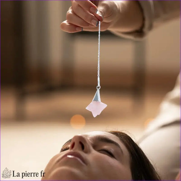 Pendule Merkaba (Quartz Rose) forme étoile géométrique tenu délicatement - La Pierre Fr