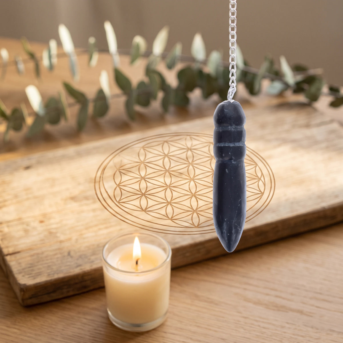 Pendule noir égyptien en shungite pour la radiesthésie sur planche Fleur de Vie
