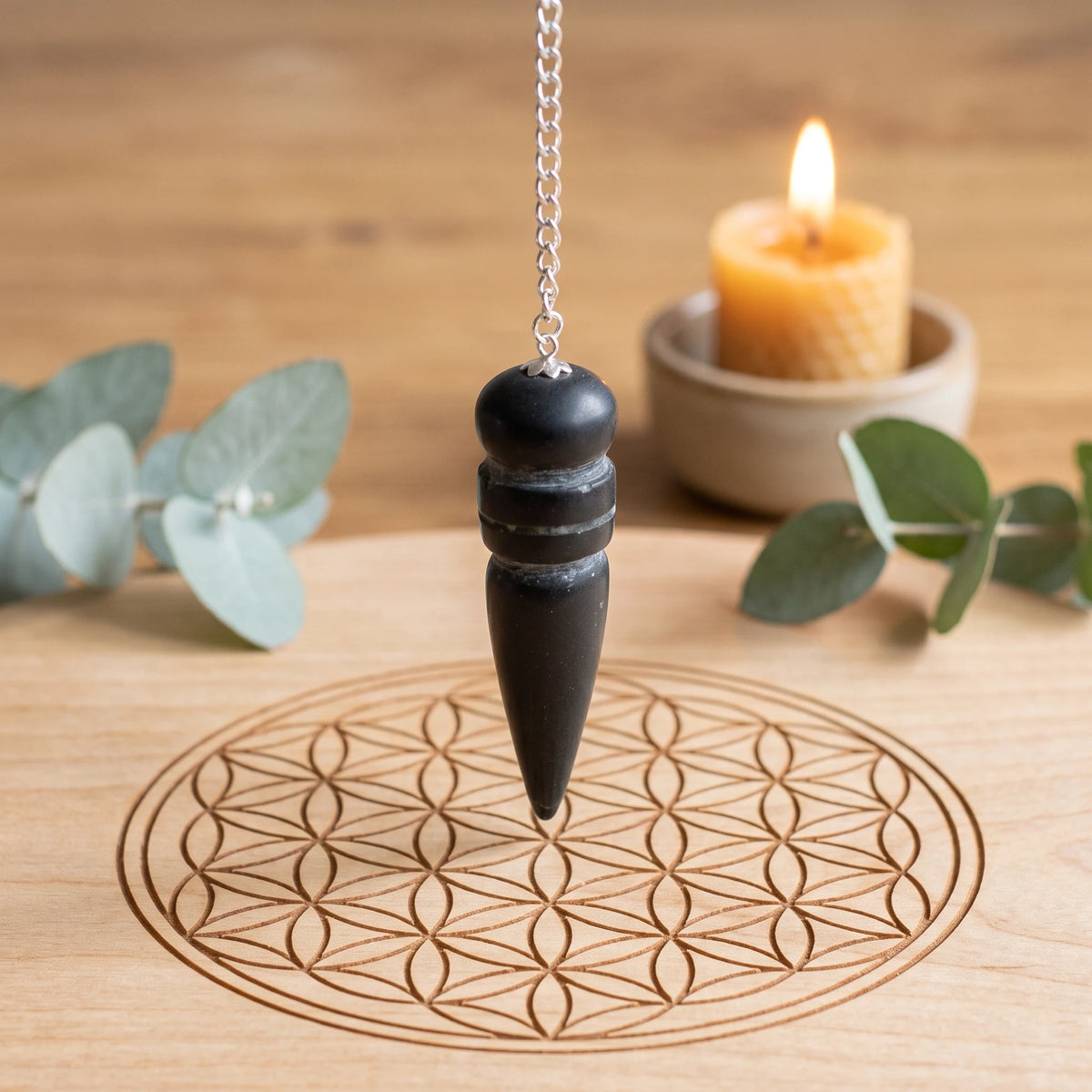 Pendule noir égyptien en tourmaline pour la radiesthésie sur planche Fleur de Vie