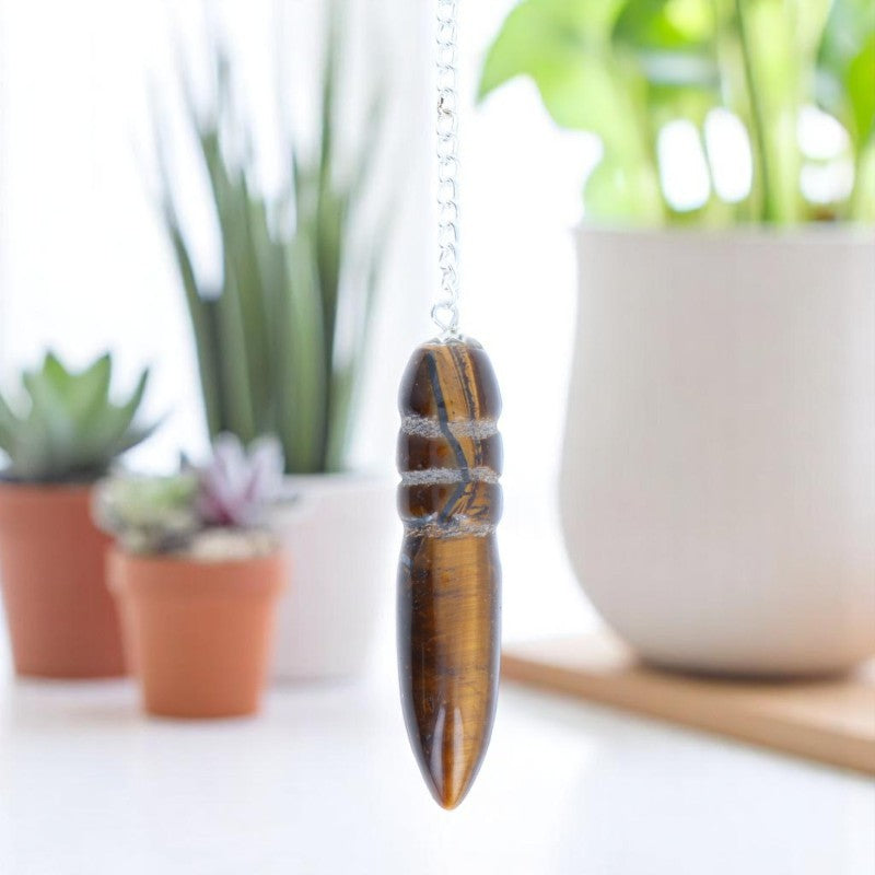 Pendule confiance Égyptien (Oeil de Tigre) avec chaîne argentée sur fond texturé