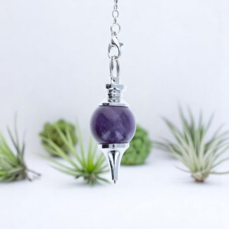 Gros plan sur la sphère et la pointe du Pendule Séphoroton (Améthyste) en pierre violette