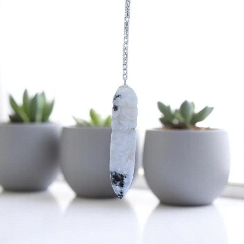 Pendule Égyptien (Pierre de Lune) avec reflet bleuté tenu délicatement - La Pierre Fr