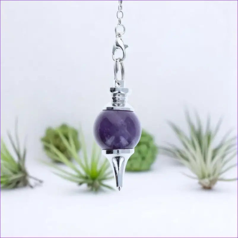 Gros plan sur la sphère et la pointe du Pendule Séphoroton (Améthyste) en pierre violette