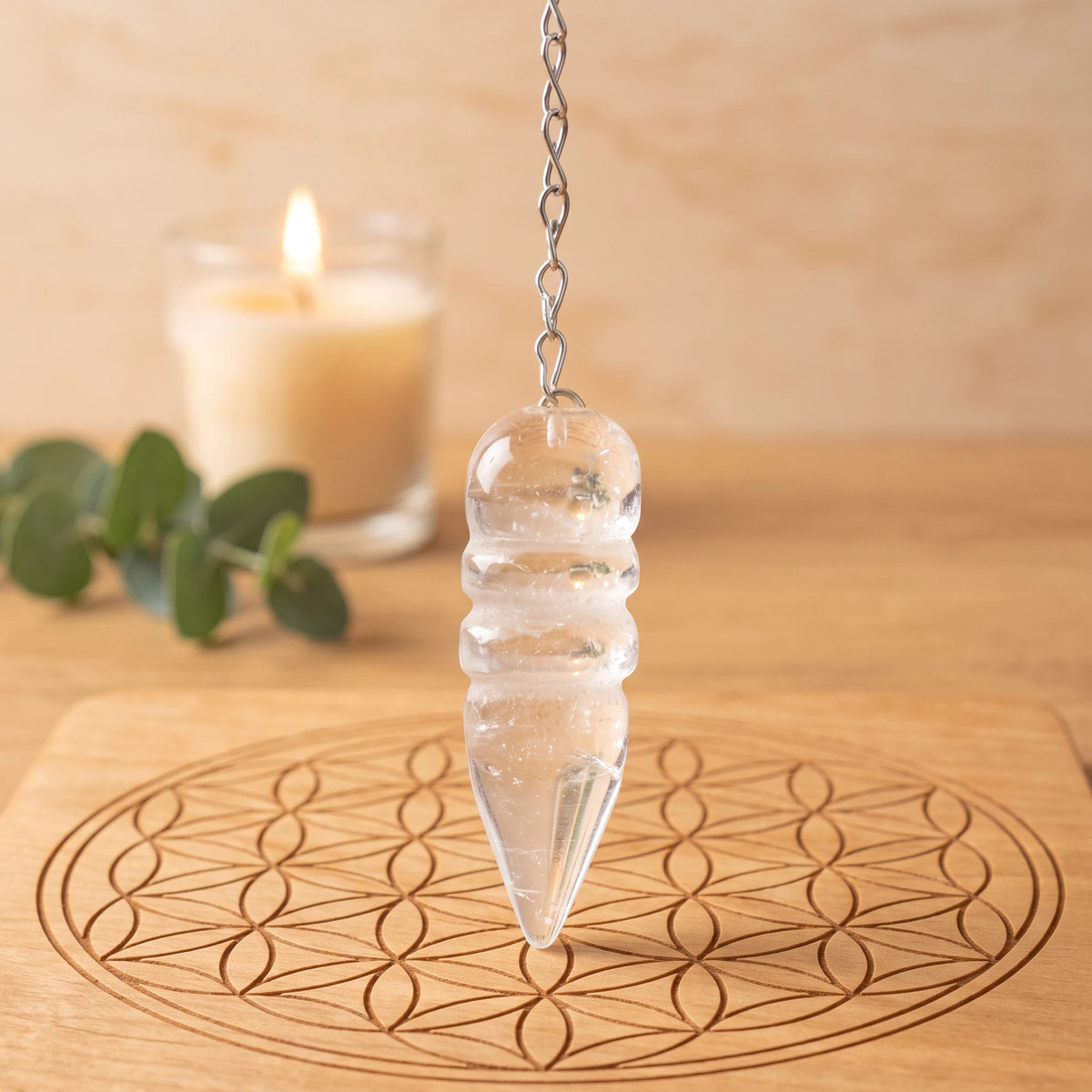 Pendule transparent égyptien en cristal de roche pour la radiesthésie sur planche Fleur de Vie