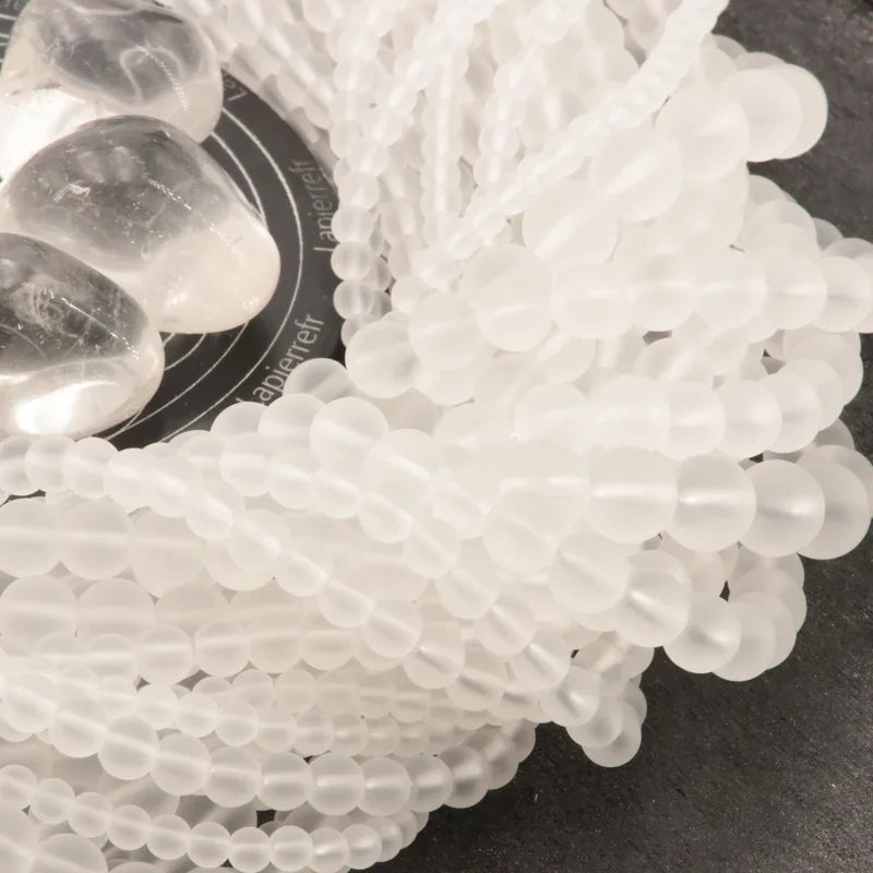 Gros plan sur des perles de Cristal de Roche dépoli, pierre naturelle au fini mat pour bracelet et collier