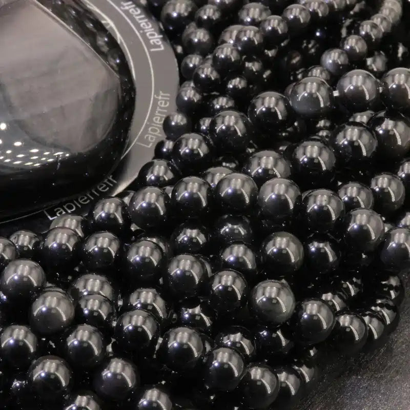 Gros plan sur des perles d'Obsidienne Noire, pierre naturelle protectrice pour bracelet et collier