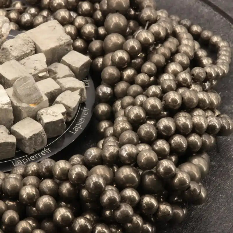 Gros plan sur des perles de Pyrite aux reflets or, pierre naturelle pour bracelet et collier