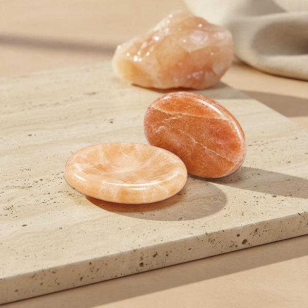 Pierre du stress en quartz orange, galet plat avec creux pour le pouce et pierre de pouce orangée sur travertin