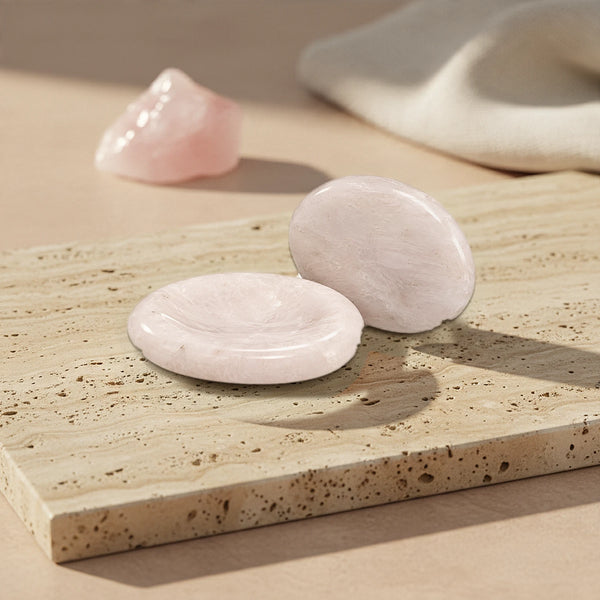 Pierre du stress rose en quartz rose, pierre de pouce douce au creux lisse, posée sur une plaque de travertin beige