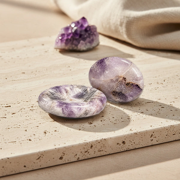 Pierre du stress violette en améthyste, deux pierres de pouce polies au creux lisse posées sur du travertin