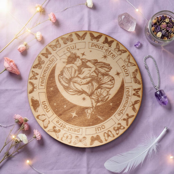 Planche pendule fée en bois gravé sur tissu lilas avec fleurs et plume