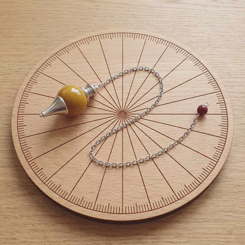 Pendule séphoroton en jaspe mokaïte sur une planche de radiesthésie
