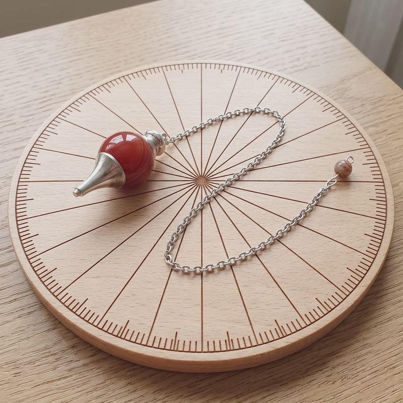 Pendule séphoroton en cornaline sur une planche de radiesthésie