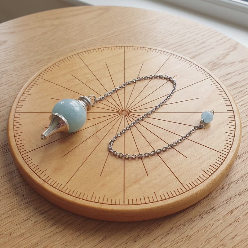 Pendule séphoroton en aigue-marine sur une planche de radiesthésie