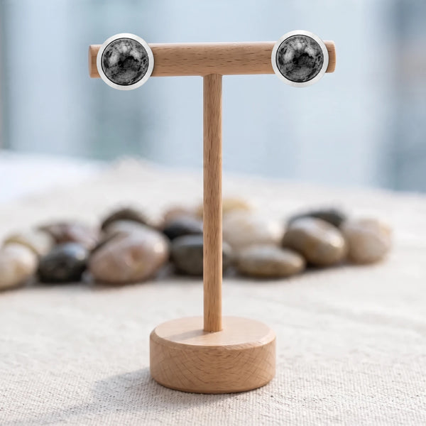 Puces d'oreilles pierre grise, cabochon de larvikite 10 mm serti en acier argenté, présentées sur un support en bois