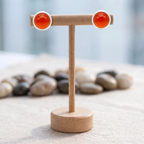 Puces d'oreilles pierre orange, cabochon de cornaline 10 mm serti sur acier argenté, posées sur un présentoir en bois
