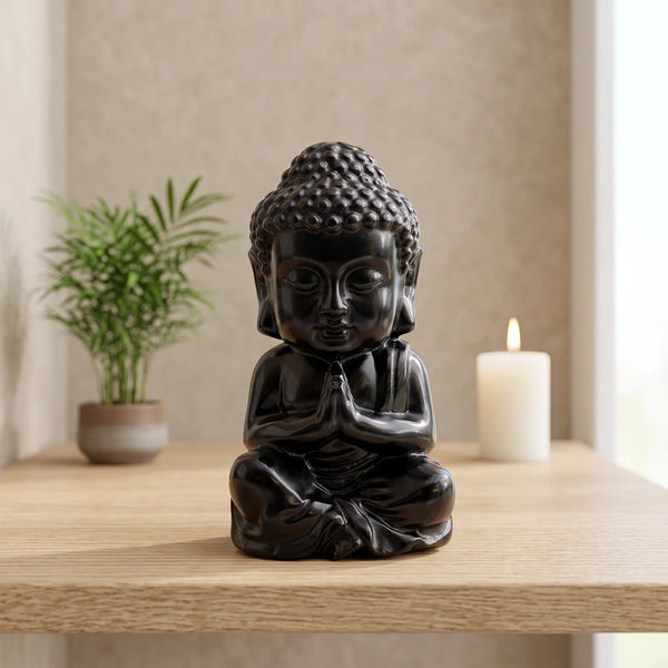 Statue Bouddha noir en obsidienne, pierre naturelle posée sur une étagère en bois