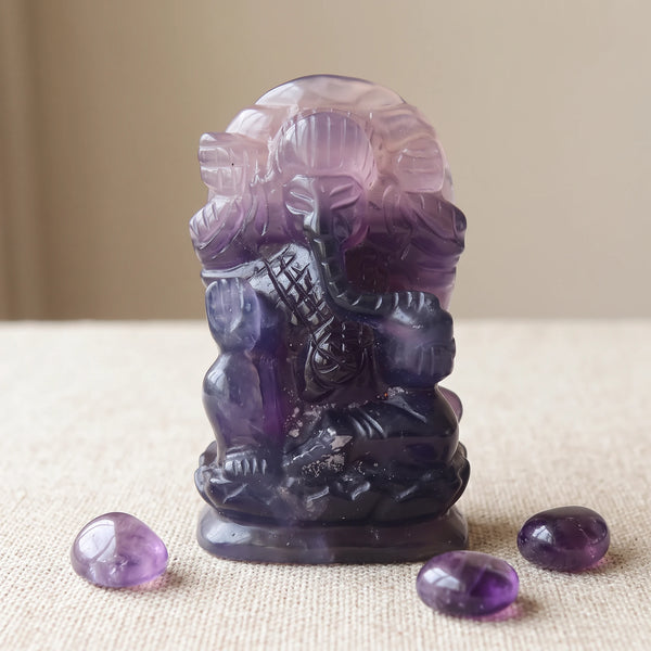 Statuette Ganesh en pierre fluorine violette avec des pierres roulées