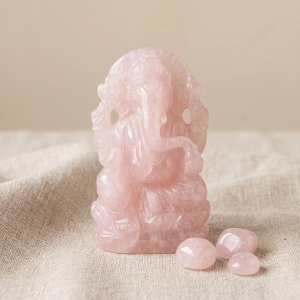Statuette Ganesha en pierre de quartz rose sur un lin naturel avec trois pierres roulées